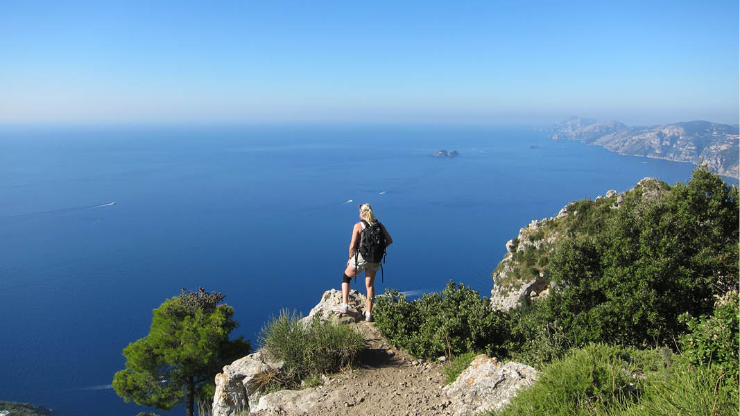Kvinna p toppen av en klippa med vacker utsikt ver Amalfikusten