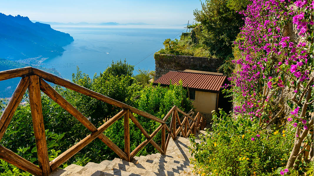 Stentrappa med blommor och vacker utsikt ver Amalfikusten i Italien