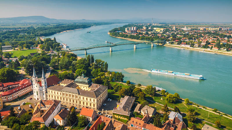 Esztergom frn ovan vid floden Donau med stadsidyll, bro och kryssningsbt.