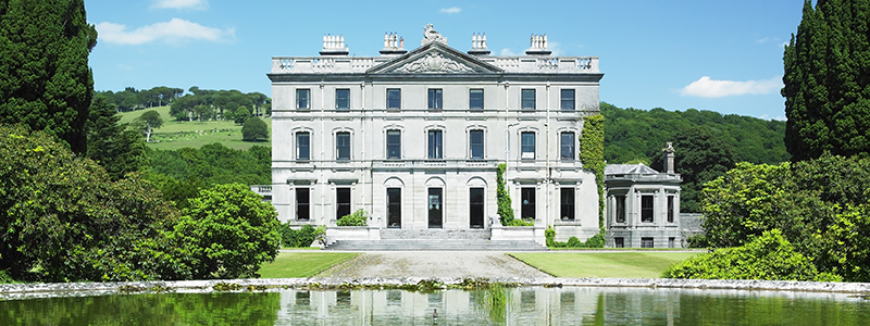 Den ståtliga vita herrgården Curraghmore vid sjön i gröna miljöer i Waterford, Irland.