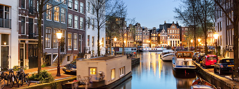 Amsterdam med sina kanaler och hus i gatubelysning.