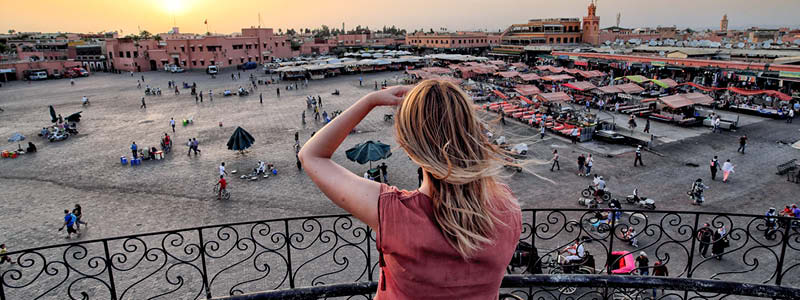 Kvinna kollar ut över Djema El-fna platsen i Marrakech Marocko vid solnedgången.