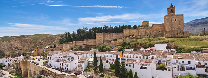 Delar av det historiska Antequeras vitputsade hus och mäktiga stadsmur.