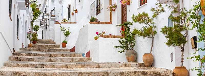 Trappa uppför vita hus och blomkrukor i byn Frigliana, Andalusien.
