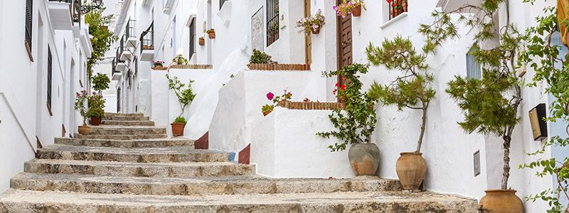 Trappa uppför vita hus och blomkrukor i byn Frigliana, Andalusien.