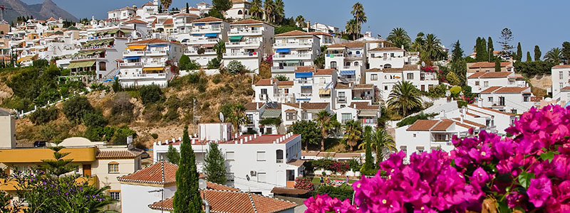 Byn Nerja med vita små hus och blommor, Andalusien.