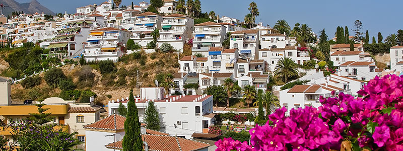 Byn Nerja med vita sm hus och blommor, Andalusien.