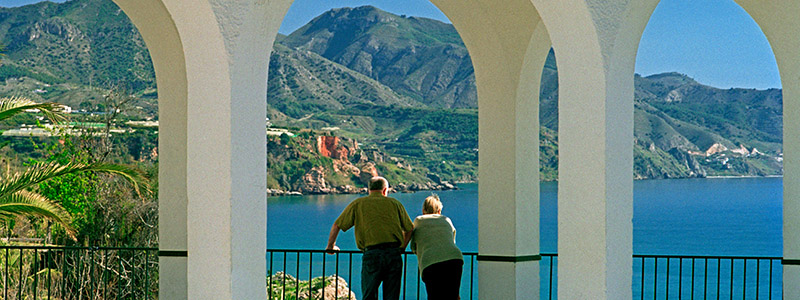Par som blickar ut över havet från en balkong i Nerja, Spanien.