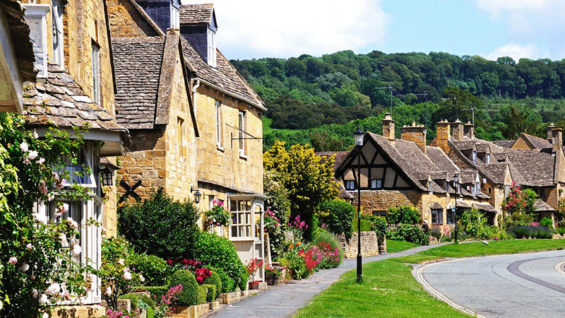 Idylliska brittiska hus p Cotswolds High Street i England.