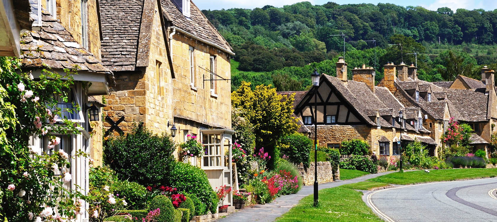 Idylliska brittiska hus p Cotswolds High Street i England.