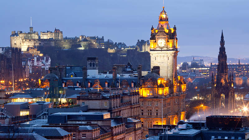 Vackra Edinburgh stad i kvllsljuset med Edinburgh Castle upplyst.