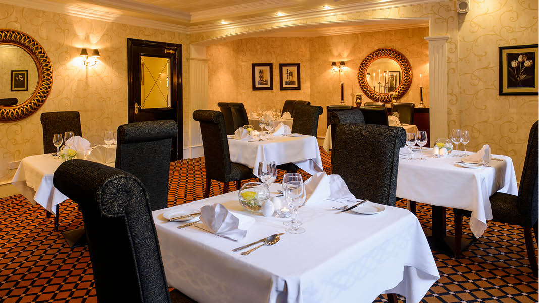 Restaurang med dukade bord p Victoria House Hotel i Killarney, Irland. 