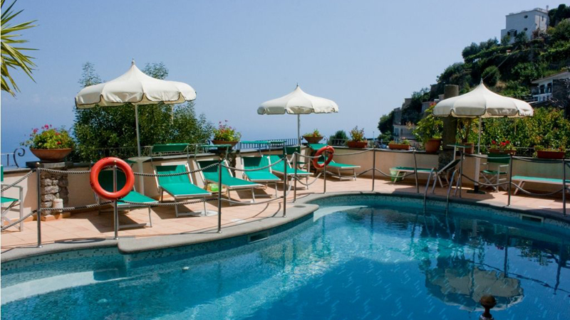 Pool med solstolar och parasol bland grna vxter p hotell Bonadies lngs Amalfikusten.