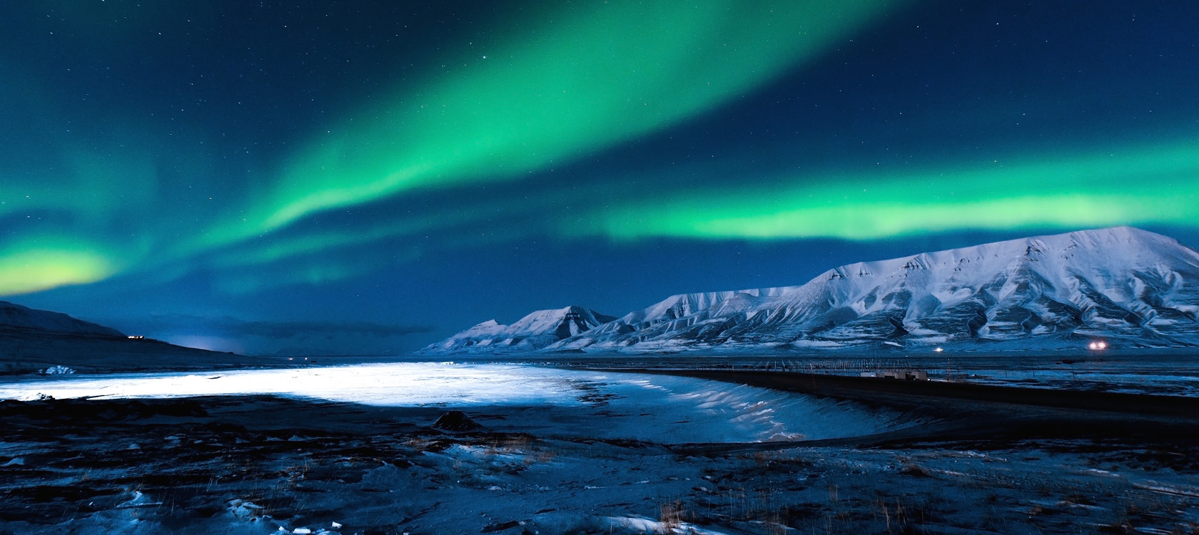 Arktisk vildmark med fjll, glacirer och norrsken p Svalbard.