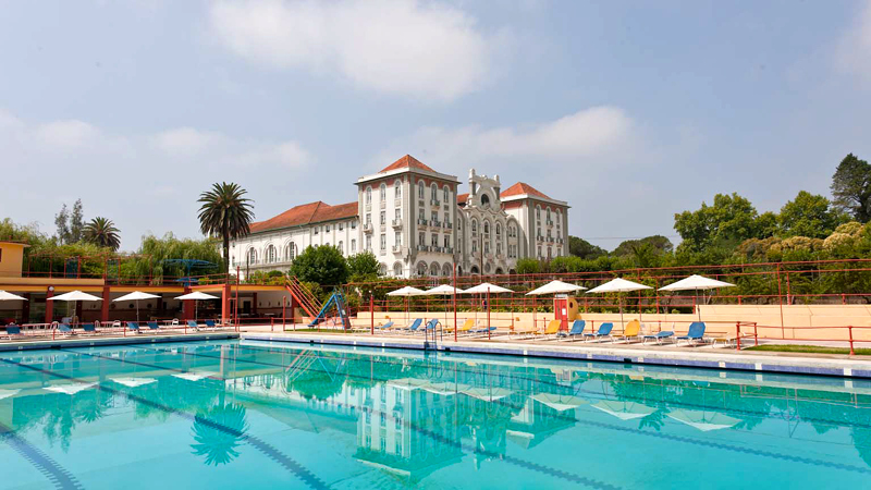 Rymlig utomhuspool med nrhet till naturen vid det gamla badhotellet Curia Palace i Portugal.