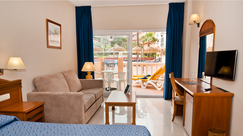 Dubbelrum med vardagsrum och terrass mot poolen p hotell Bahia Tropical i Almunecar, Andalusien.