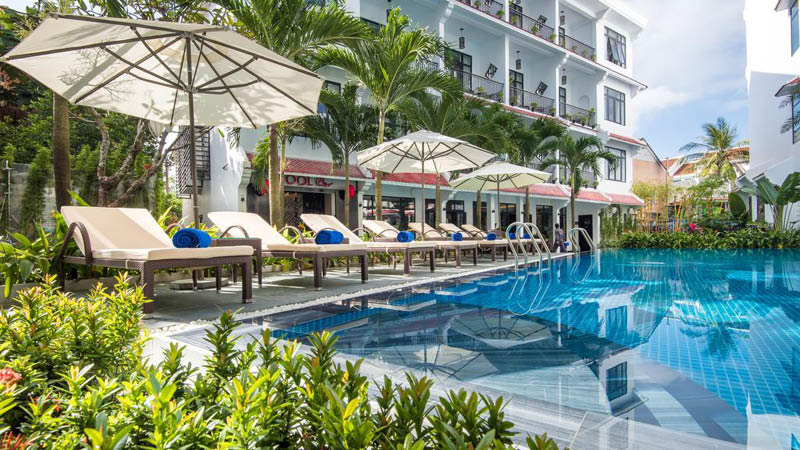 Utomhuspool med solstolar och palmer p det fyrstjrniga hotellet Belle Maison Hadana Resort and Spa i Hoi An, Vietnam.